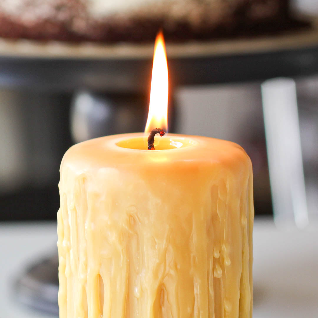 Burning candle with melting wax dripping over a candle hol…
