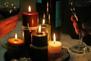 a grouping of pure beeswax pillar candles burning next to a wine glass